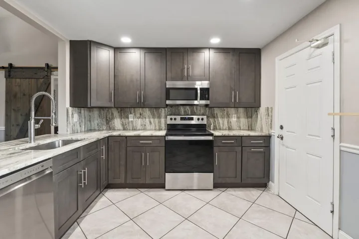 Kitchen featuring dark wood-finish cabinetry, light-toned countertops, a stainless steel sink, and stainless steel appliances