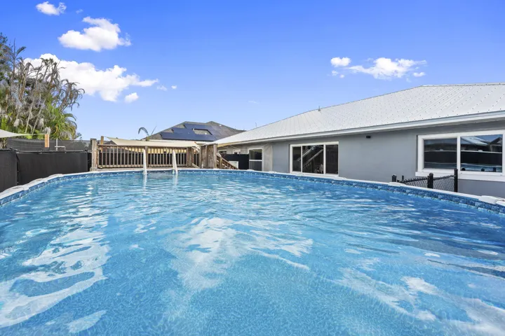 Outdoor swimming pool with a wooden deck and a gray exterior home