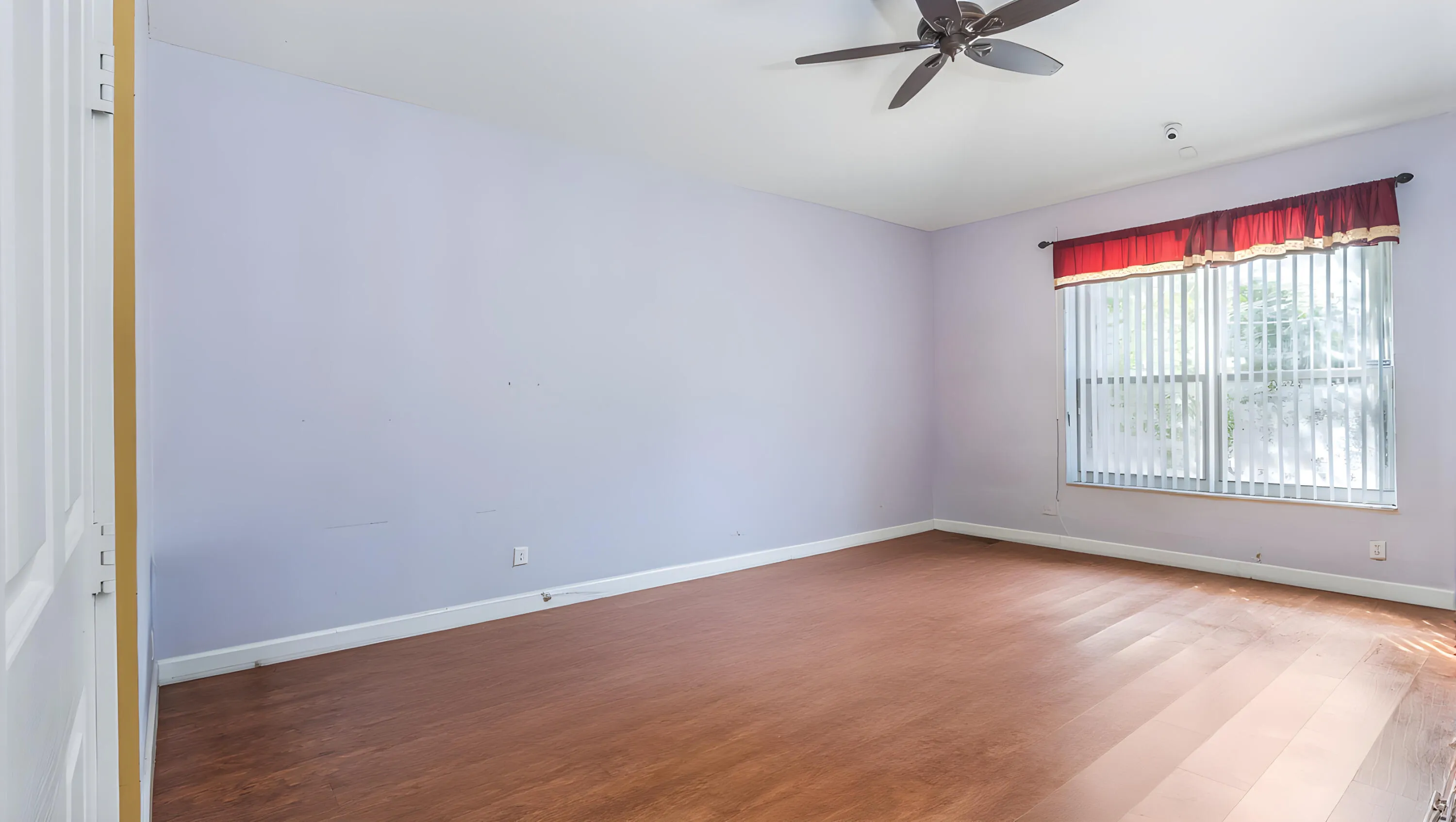 Wood-finish flooring, ceiling fan, and window with vertical blinds