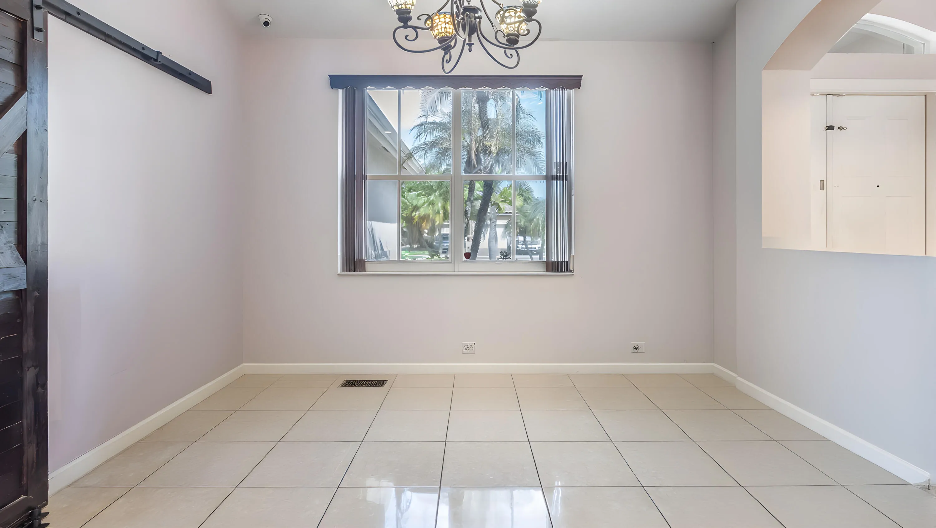 Tile flooring, traditional chandelier, window with exterior scenery, half-wall with archway, barn door on track