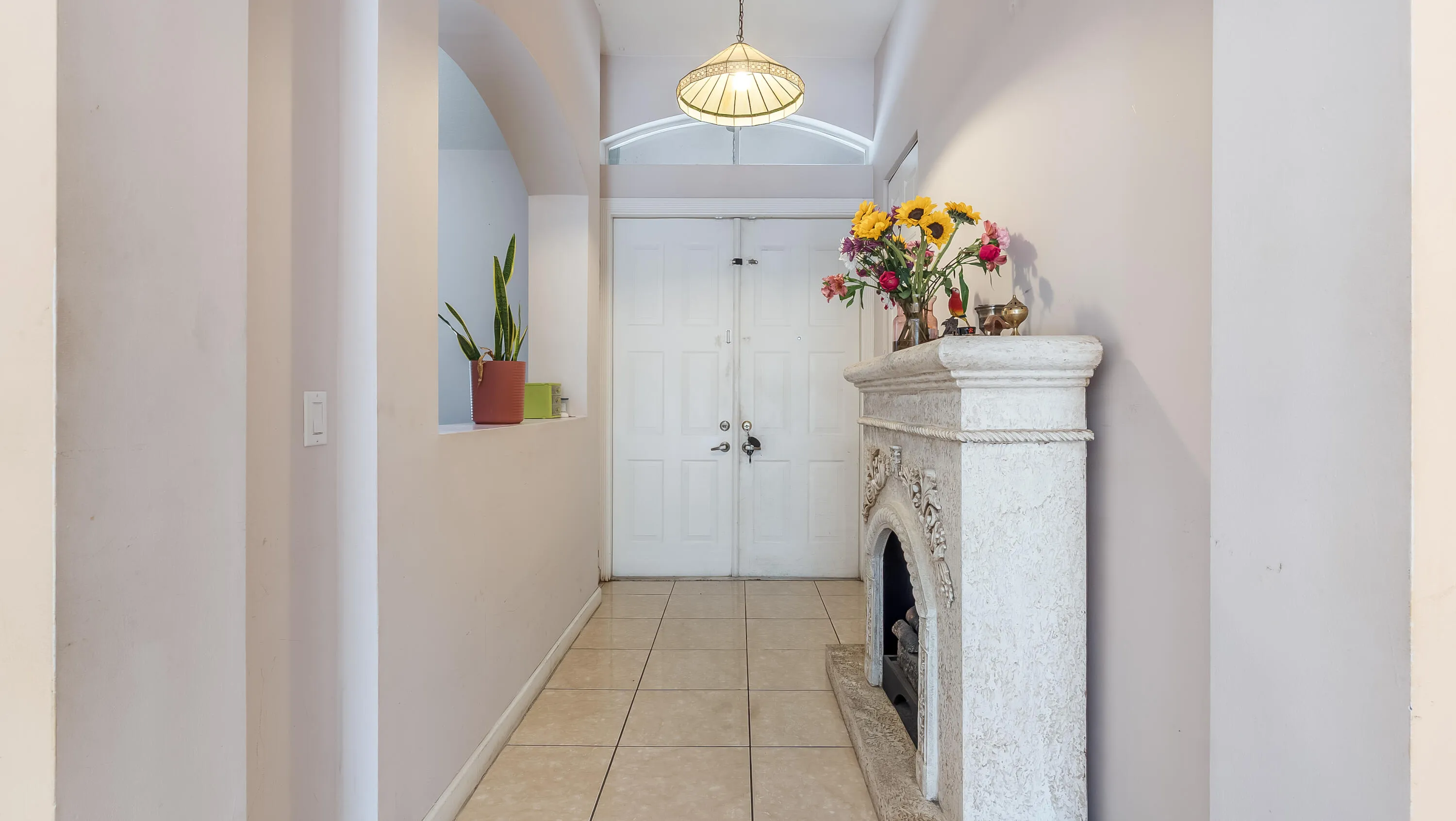 Tile flooring, overhead light fixture, arched wall opening, double entry doors