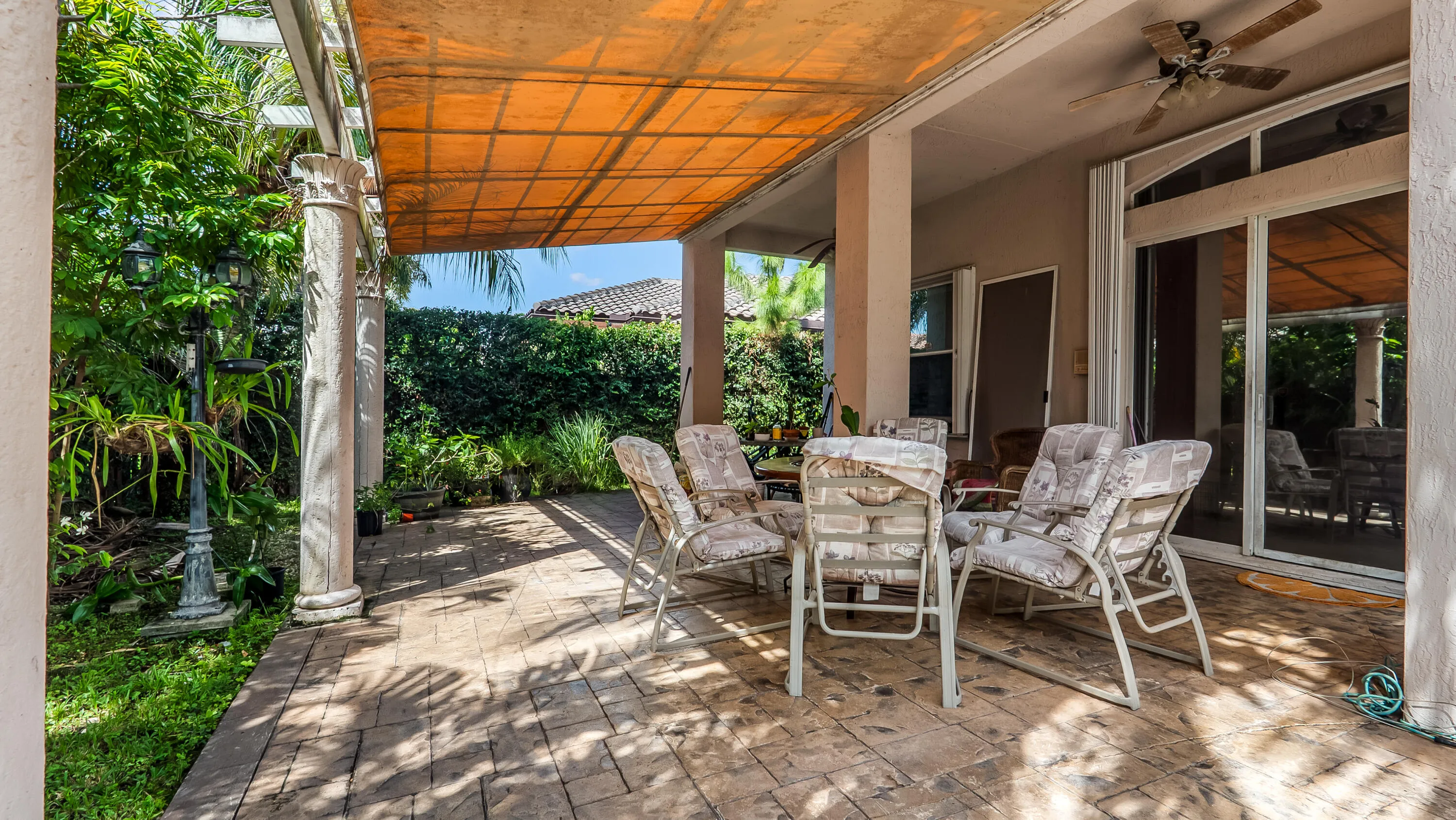 Expansive patio featuring a paver surface, decorative columns, and a covered pergola with a retractable shade