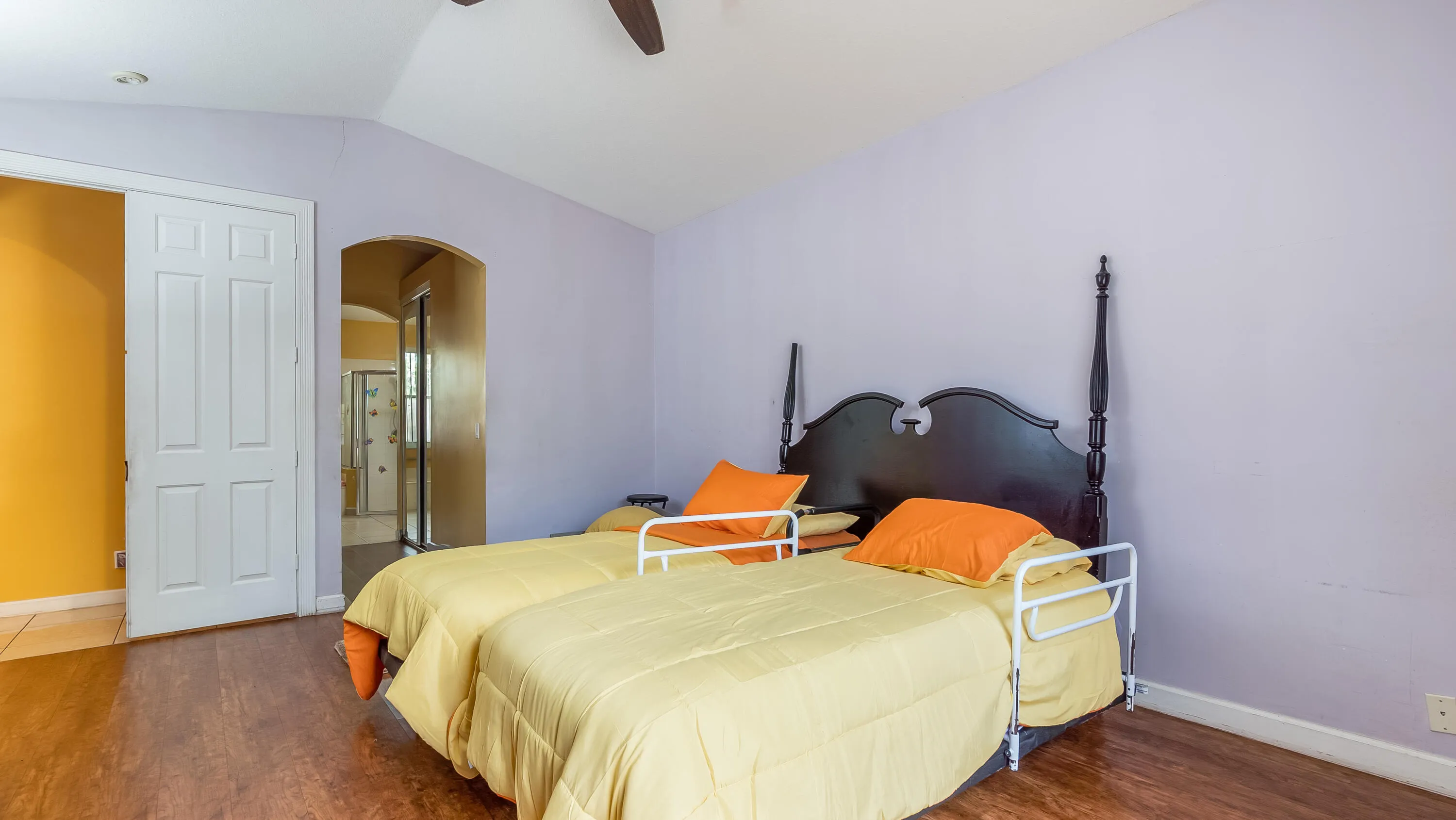 Vaulted ceiling with a ceiling fan, wood-finish flooring, and an arched doorway leading to an adjoining space
