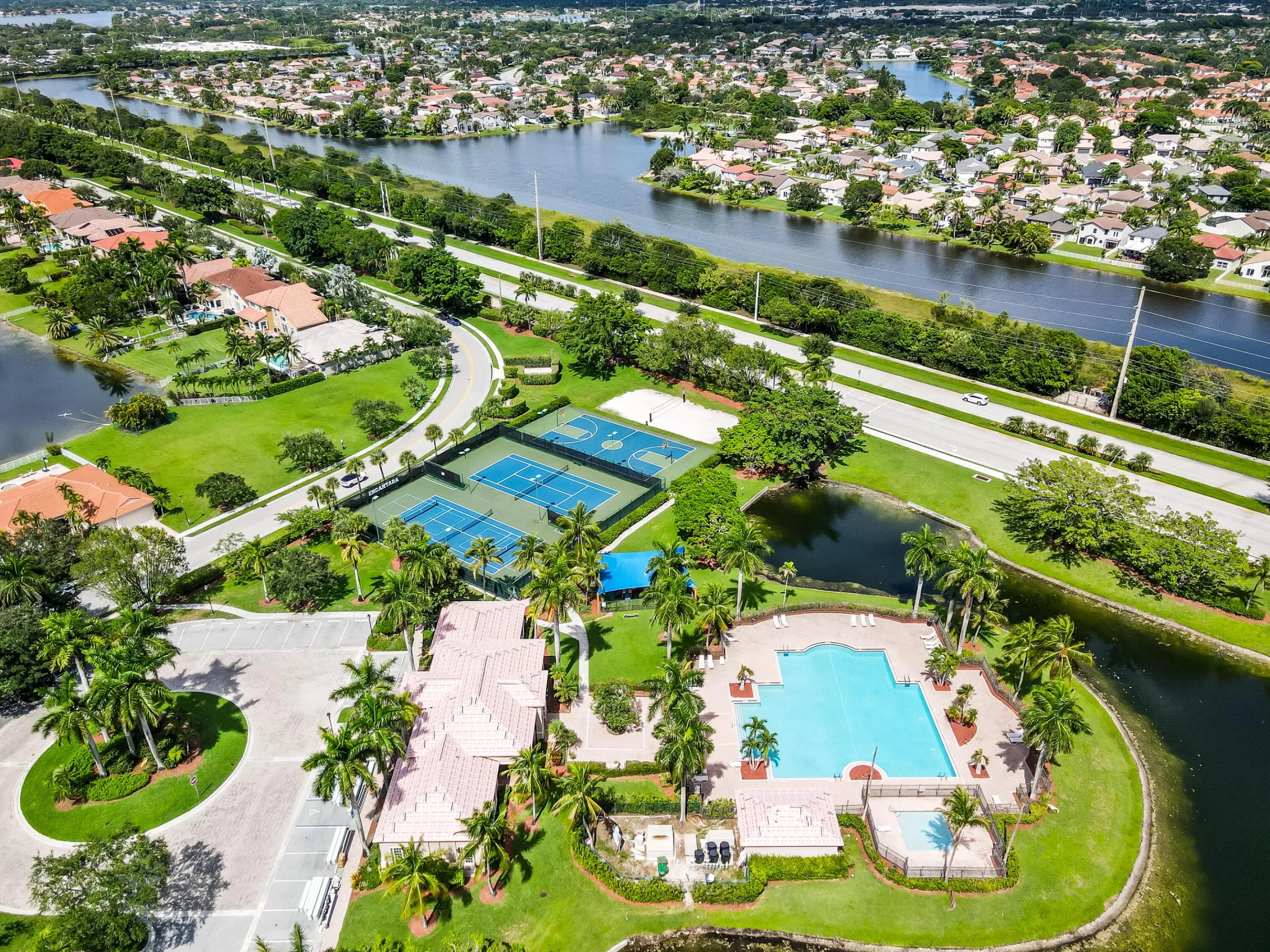 Community amenities featuring a large outdoor pool, adjacent spa, multiple tennis courts, and a sand court