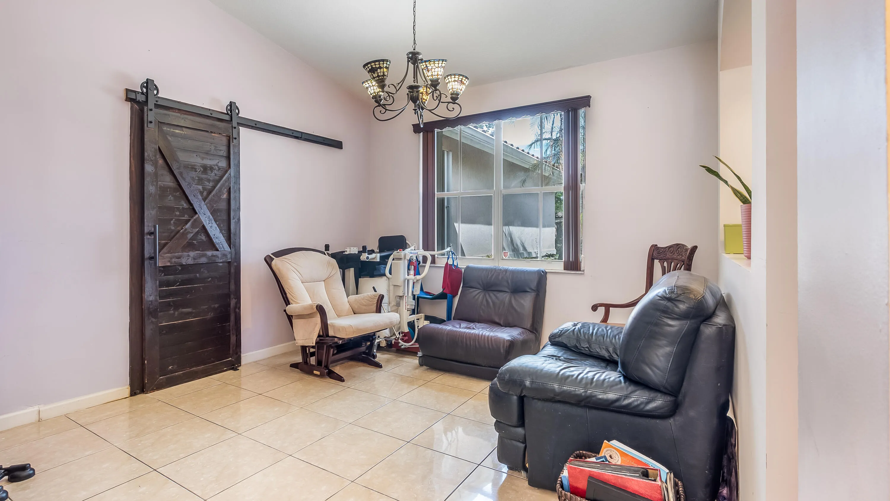 Vaulted ceiling with chandelier, dark wood-finish barn door, window with dark wood-finish frame, tiled flooring, and wall niche
