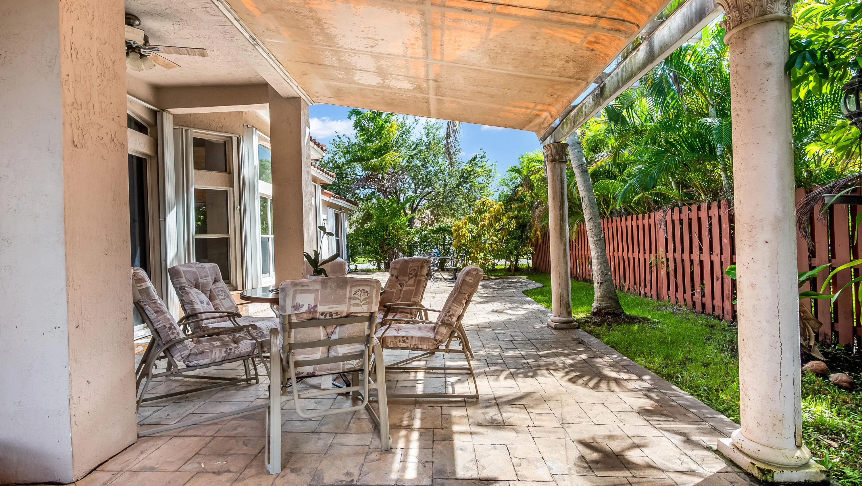 Covered patio featuring an imprinted concrete surface, classical columns, and a fabric overhead covering