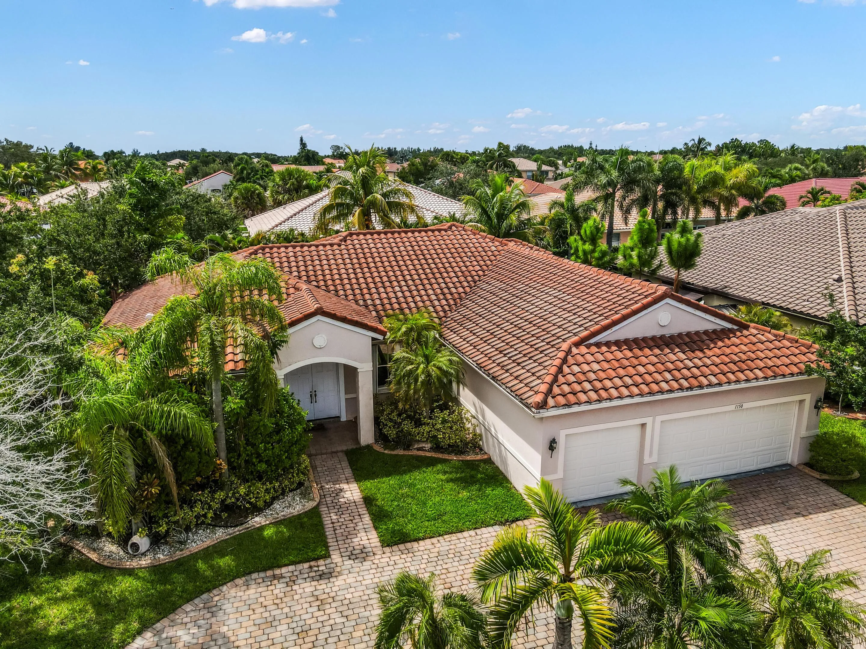 Mediterranean-style residence featuring a tile roof, dual garage doors, and a paver driveway