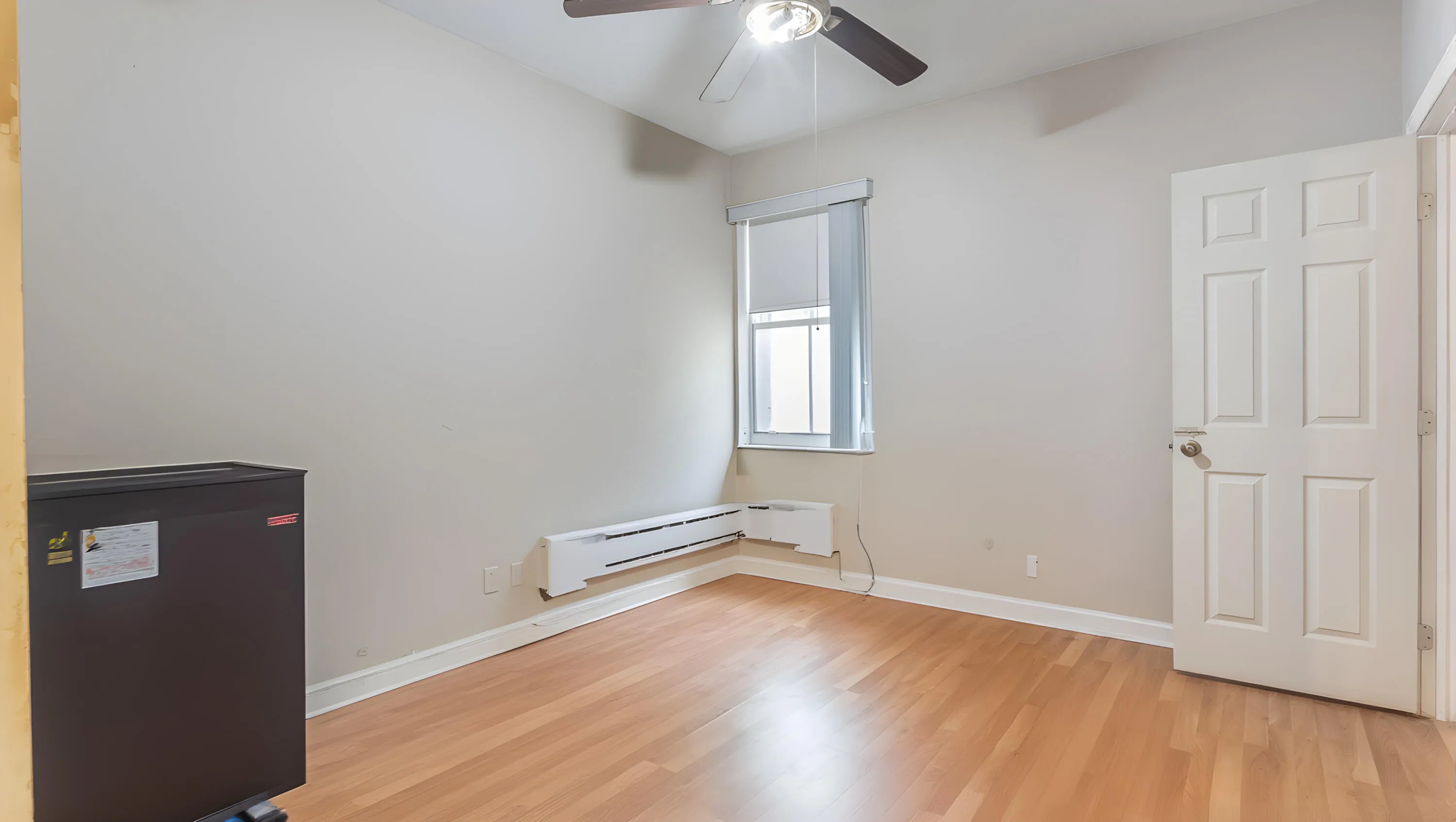 Wood-finish flooring with a ceiling fan, a window, and a paneled door