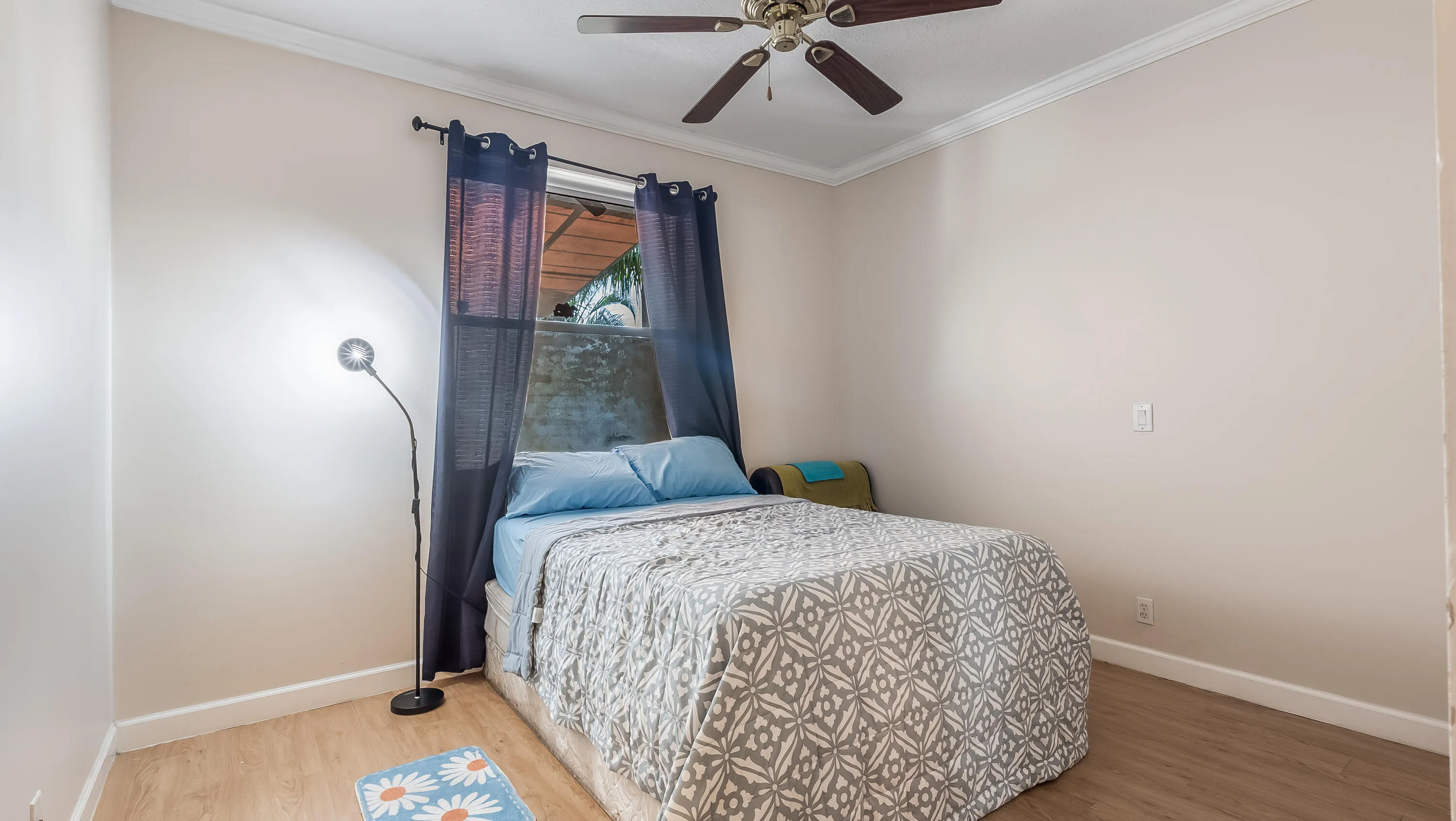 Wood-finish flooring, crown molding, and a ceiling fan with light fixture