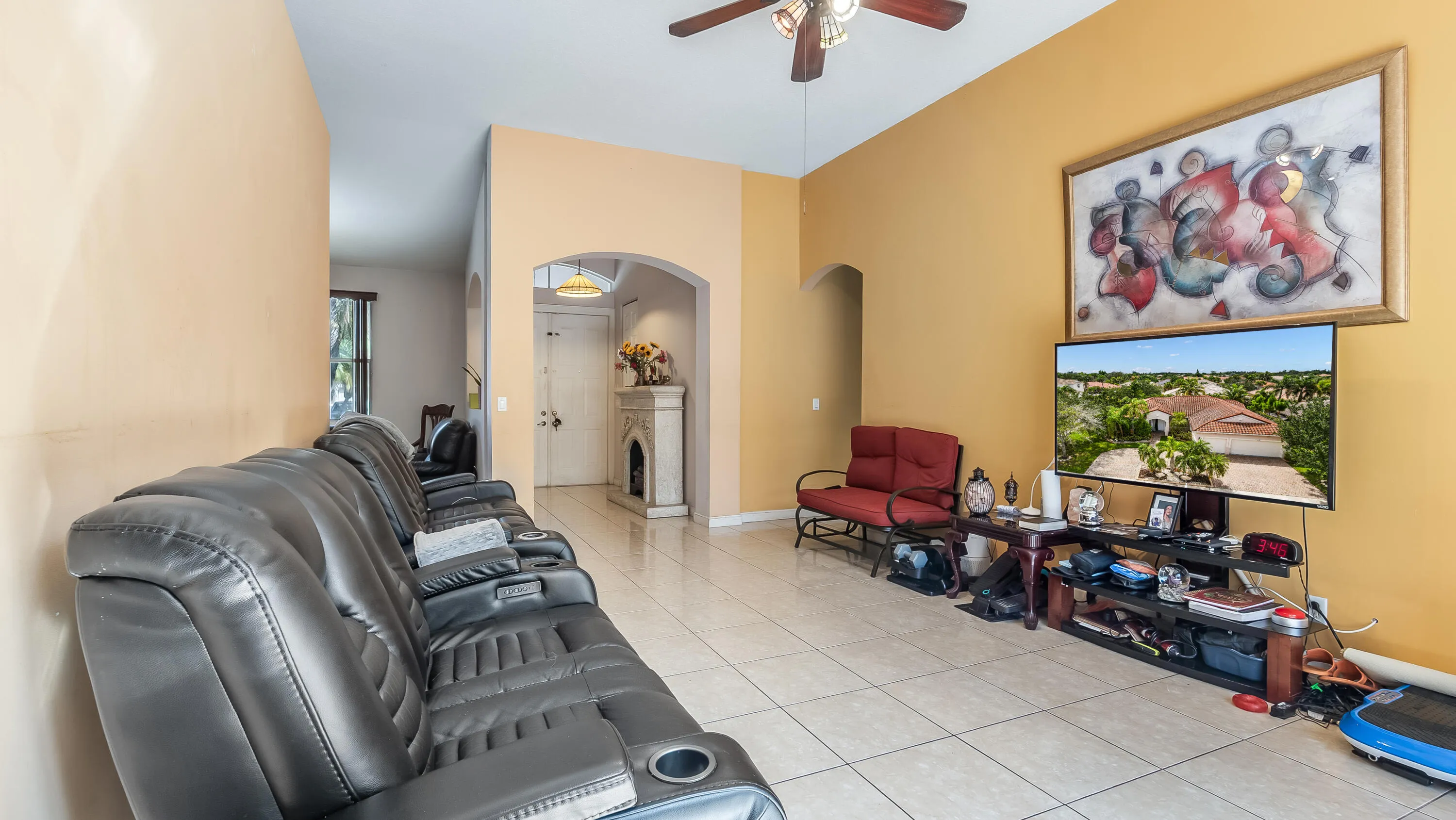 Vaulted ceilings with a ceiling fan, arched doorways, and light-toned tile flooring