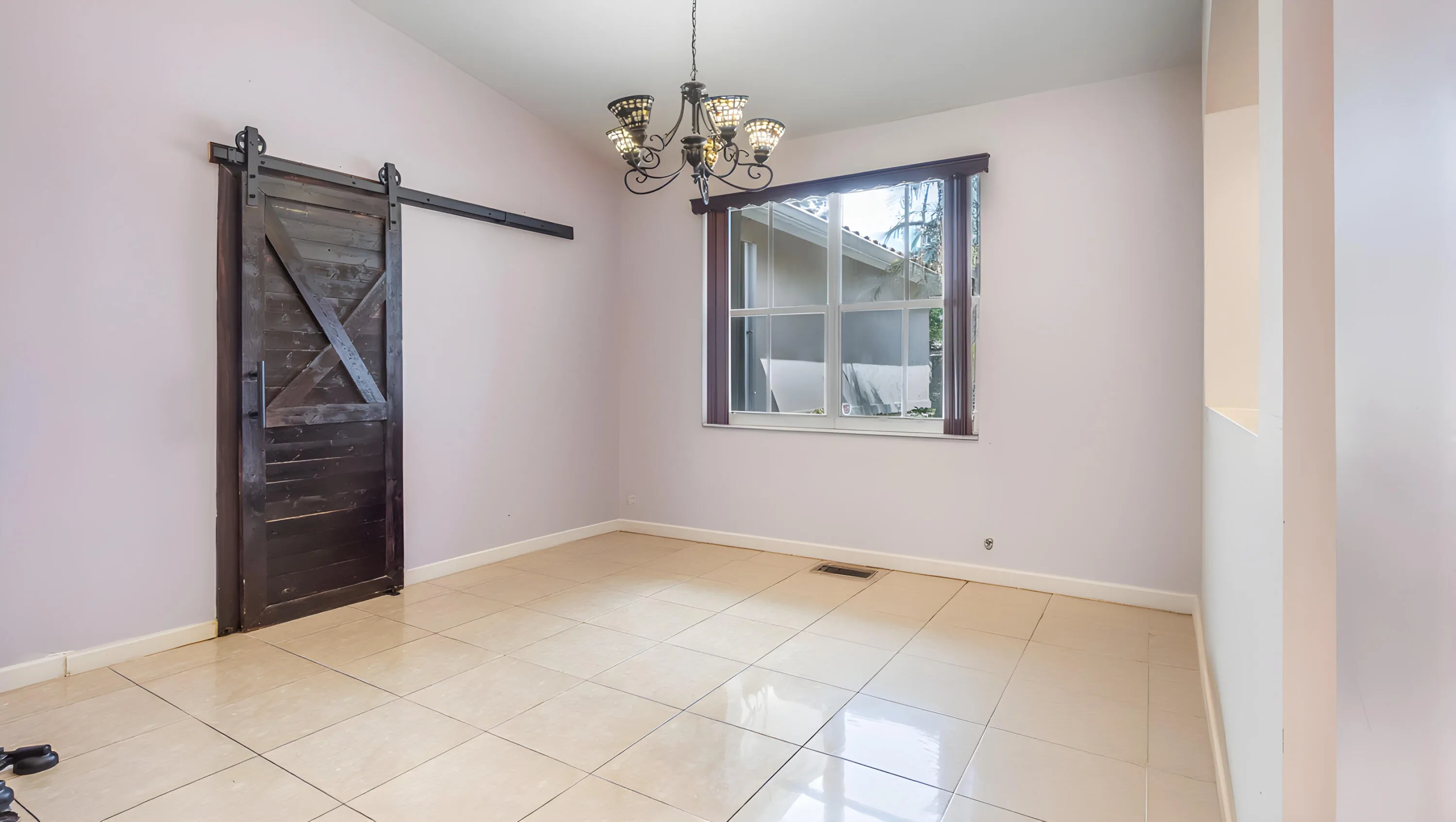 Vaulted ceiling, decorative chandelier, dark wood-finish barn door, tiled flooring, built-in wall niche