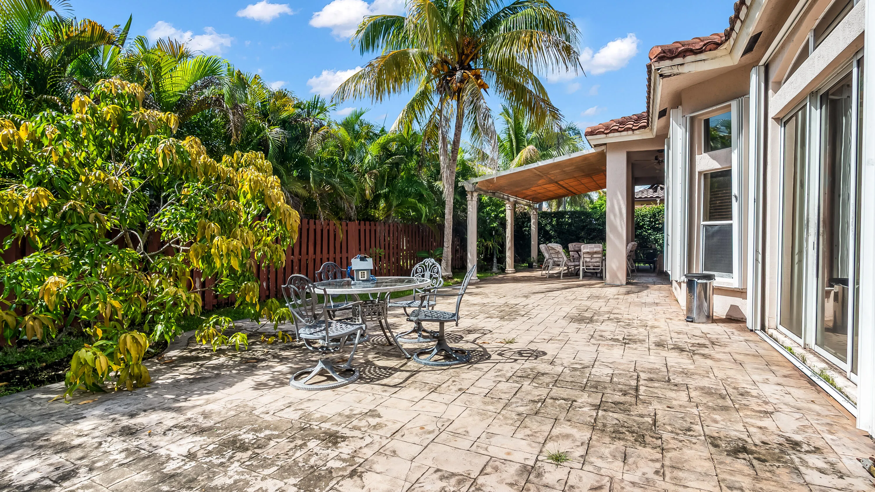 Expansive stamped concrete patio with a covered pergola and mature landscaping