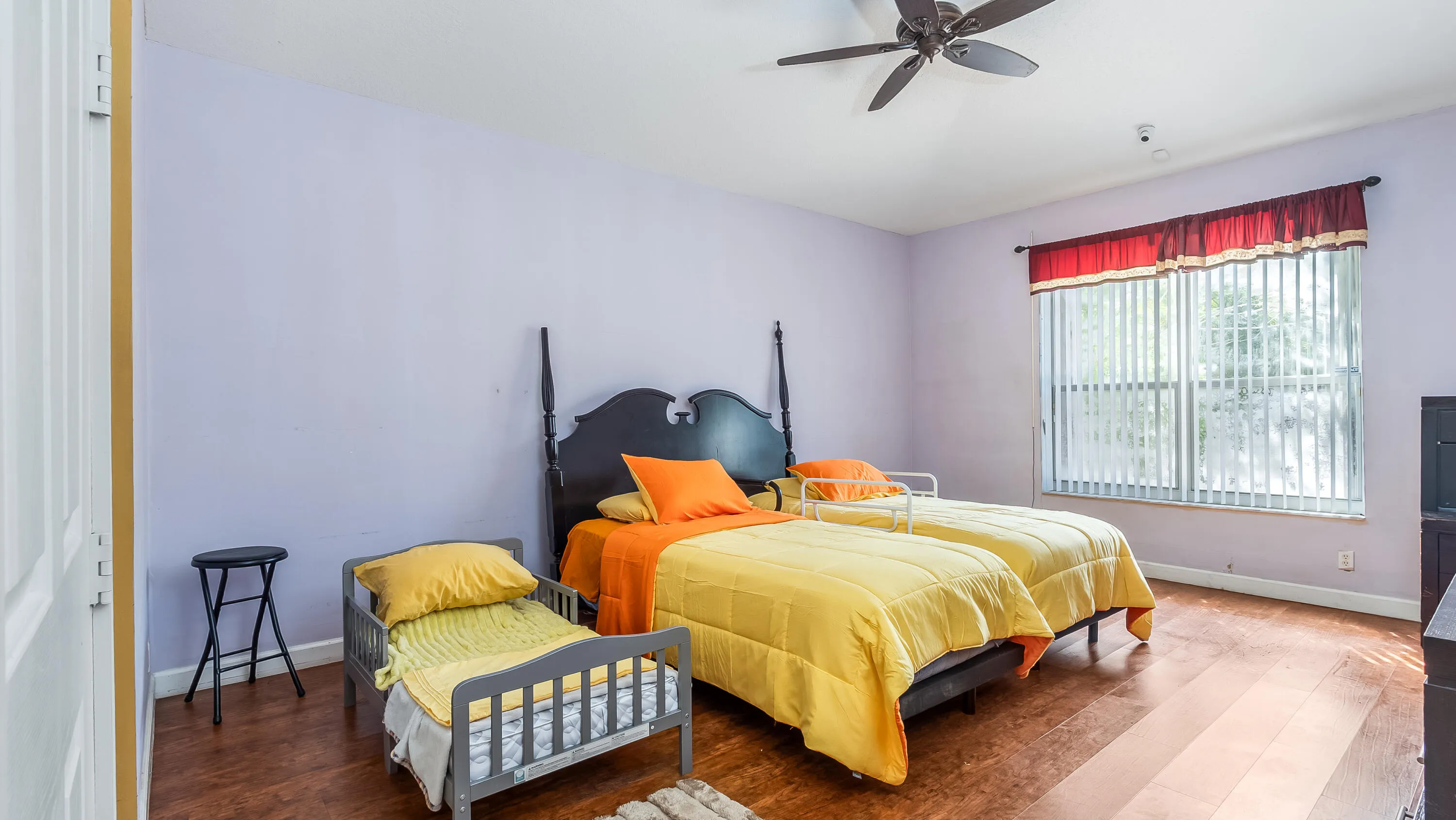 Wood-finish flooring throughout, ceiling fan, window with vertical blinds, and a built-in closet with paneled door