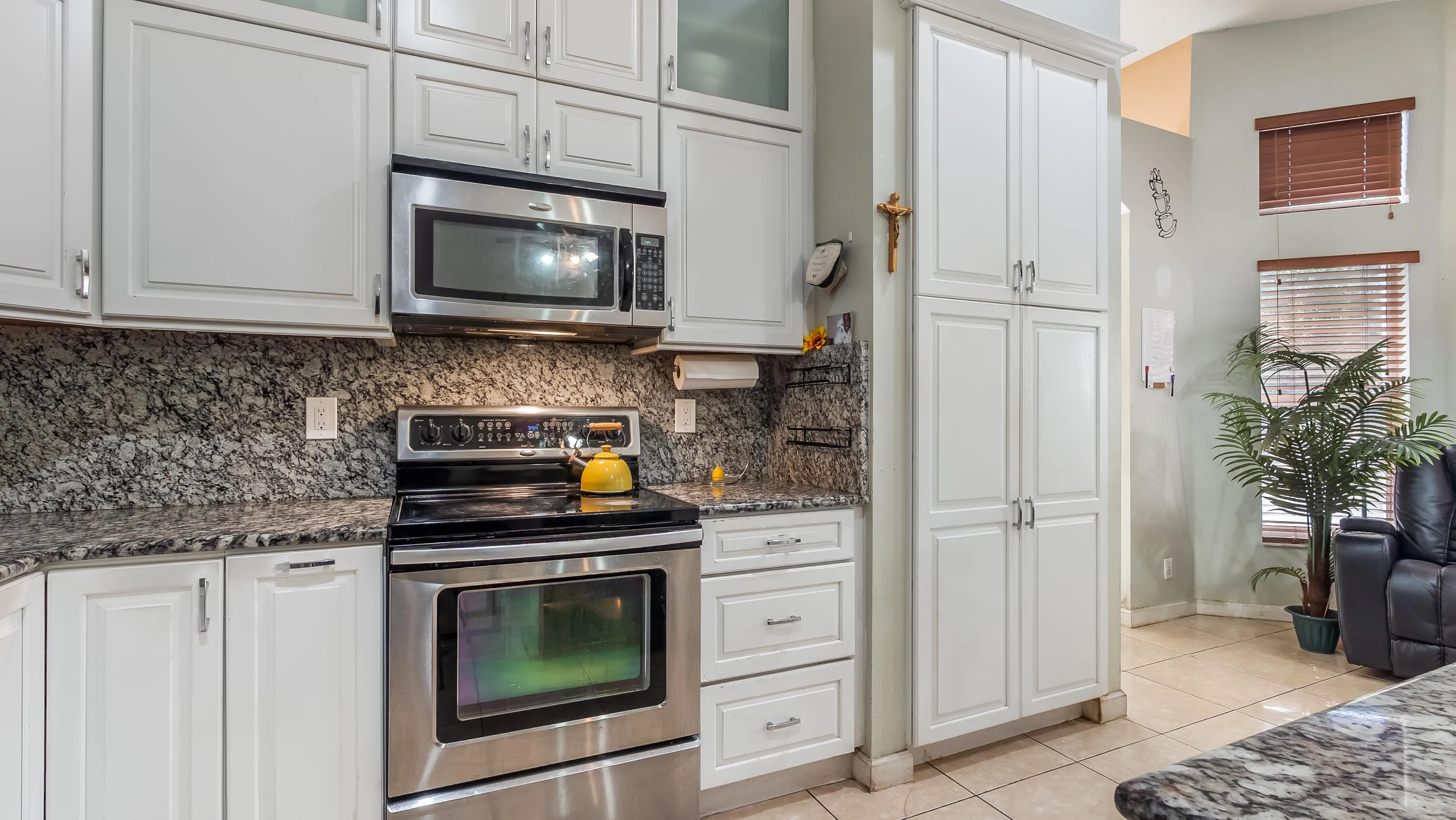 Kitchen featuring stainless steel appliances, light-toned cabinetry, and dark speckled countertops