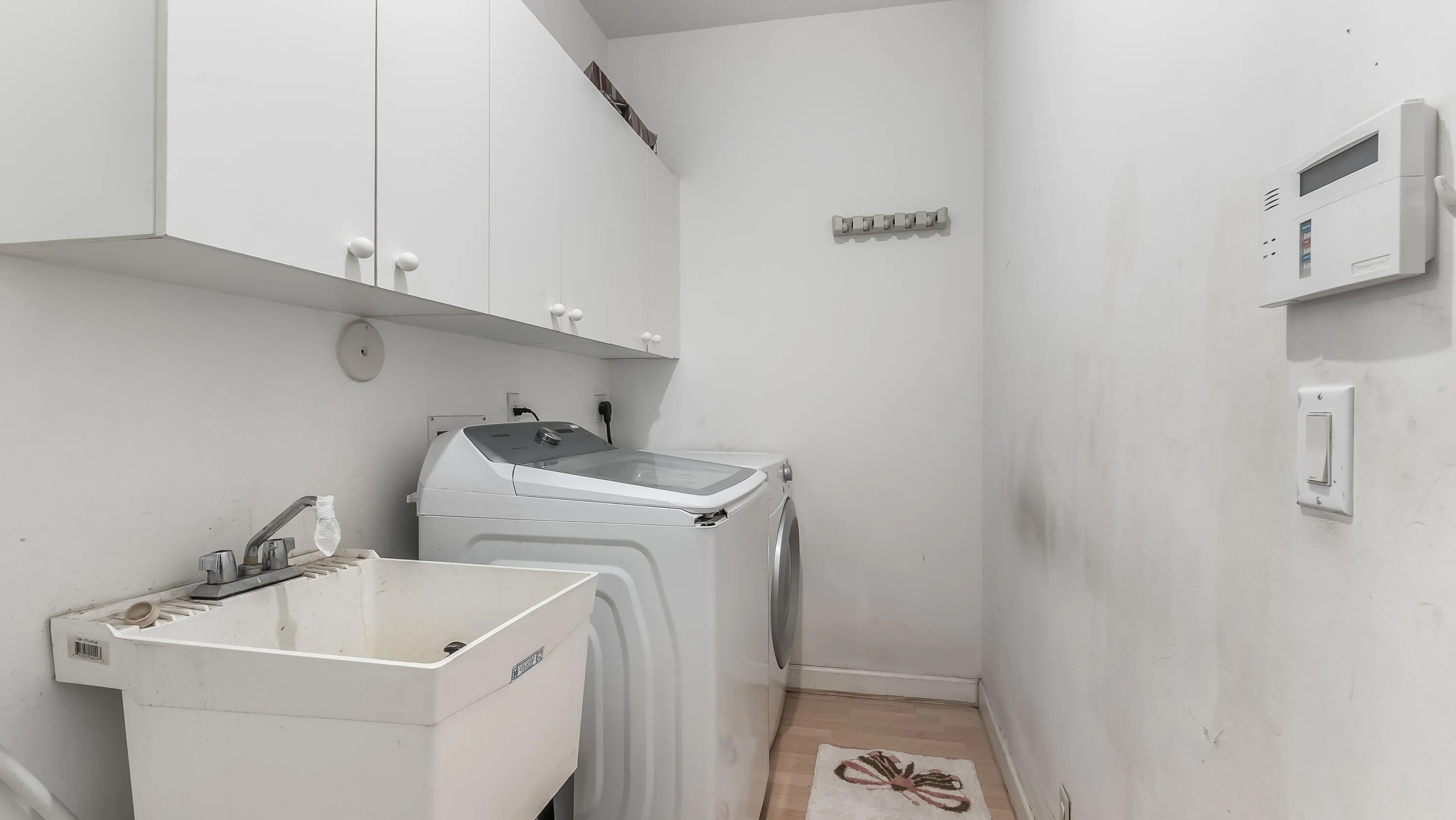White cabinetry, utility sink, and wood-finish flooring