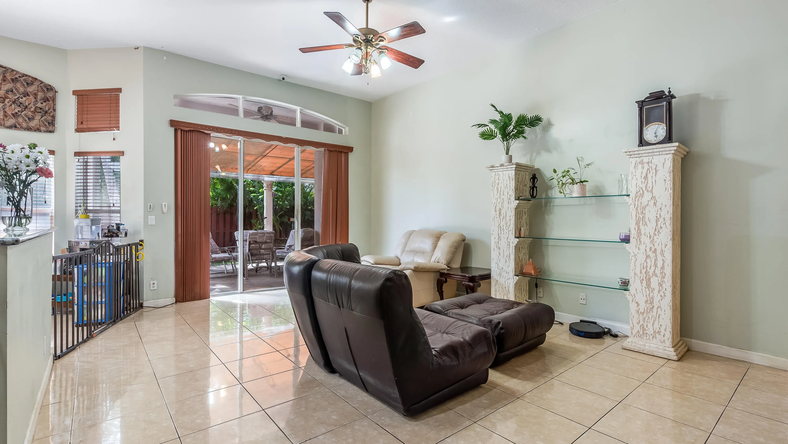 Tiled flooring, vaulted ceiling with a ceiling fan, and sliding glass doors with an arched transom window