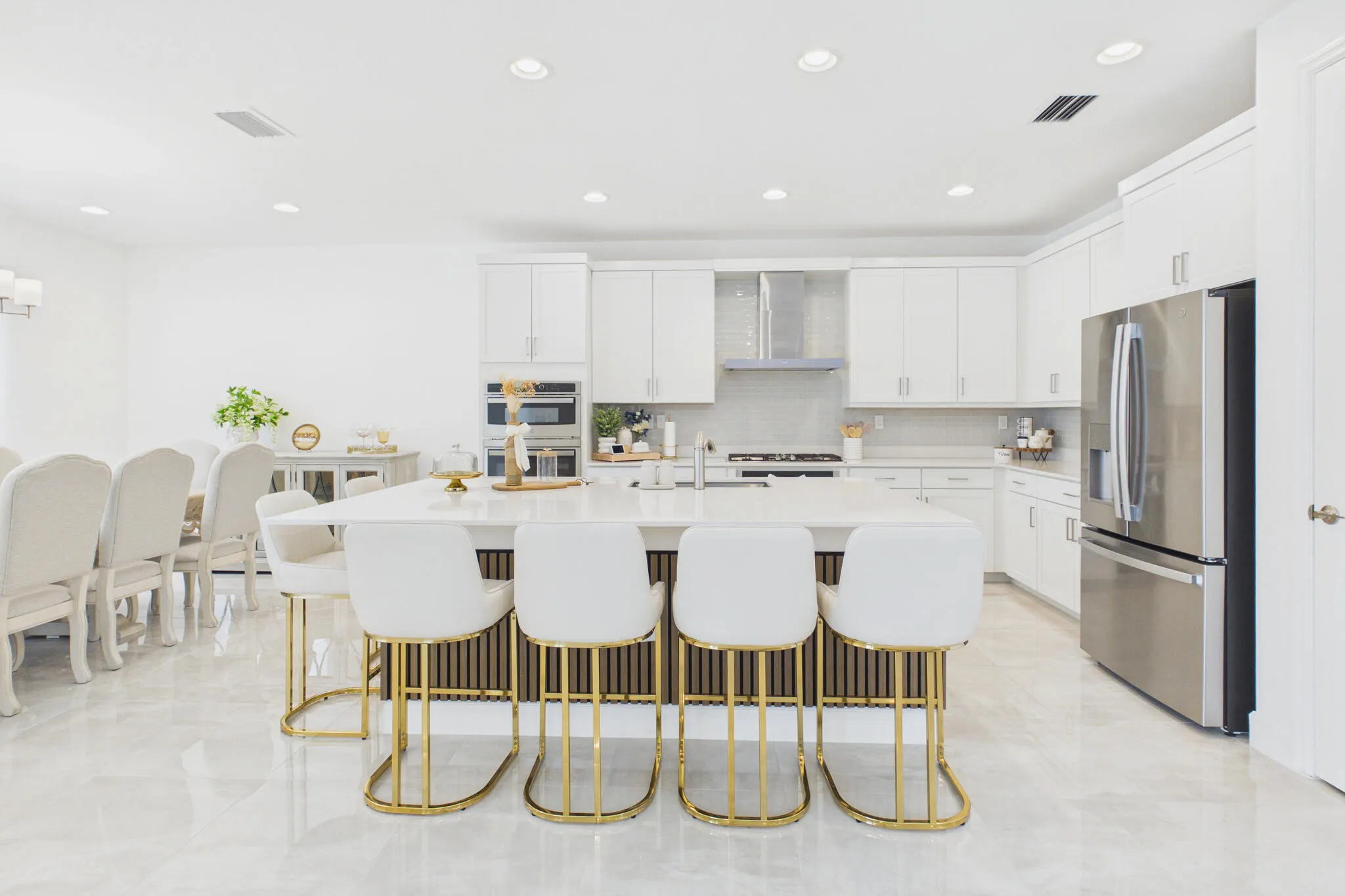 Gourmet kitchen with a large central island, stainless steel appliances, white cabinetry, and recessed lighting