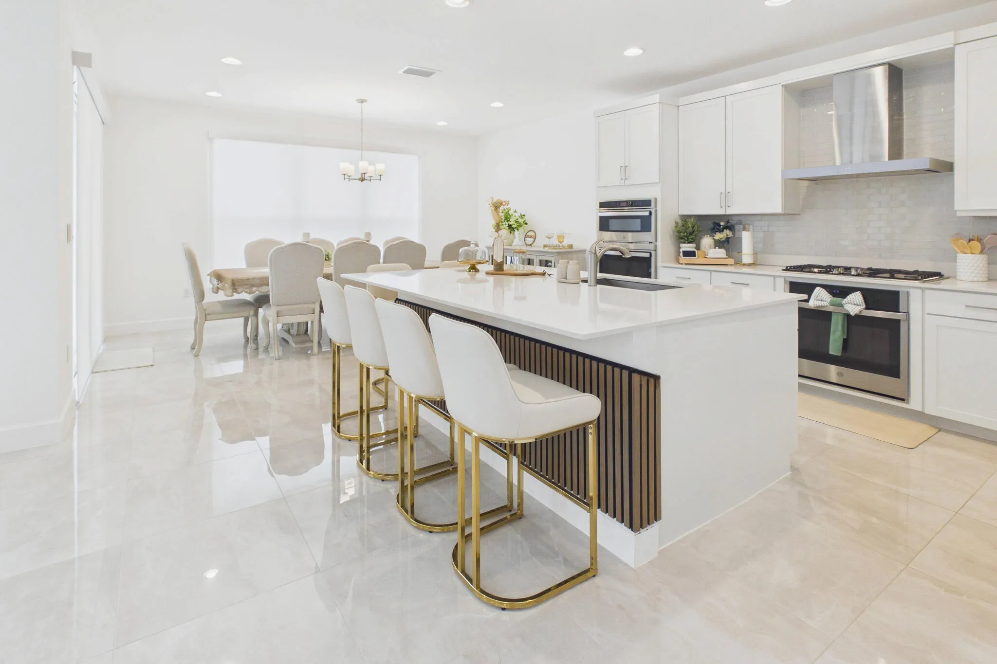Gourmet kitchen with white cabinetry, stainless steel appliances, a large center island with seating, and light-toned tile flooring