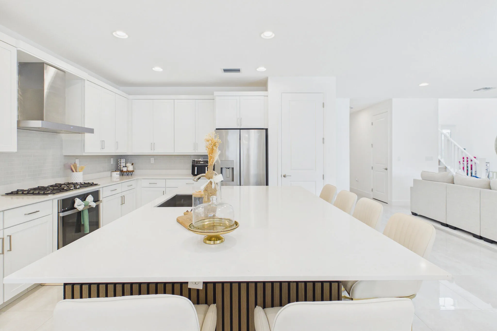 Kitchen featuring an expansive island with a solid surface countertop, white shaker-style cabinetry, stainless steel appliances, a tile backsplash, and recessed lighting