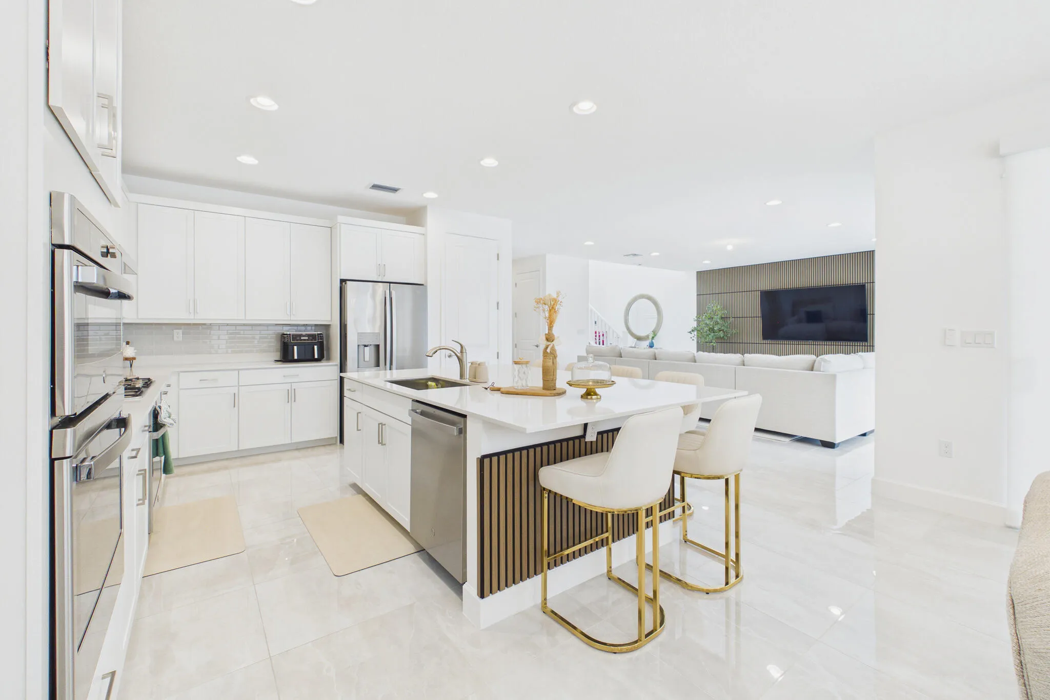 Modern kitchen featuring white cabinetry, stainless steel appliances, a center island with bar seating, and light-toned tile flooring