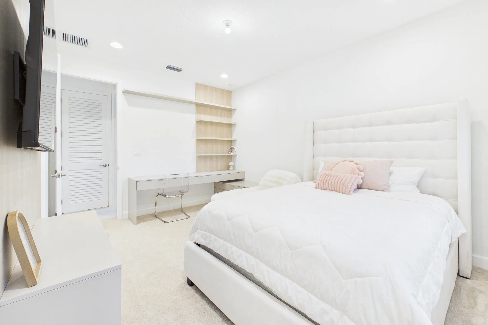 Recessed lighting, light-toned carpeting, built-in shelving, and a built-in desk
