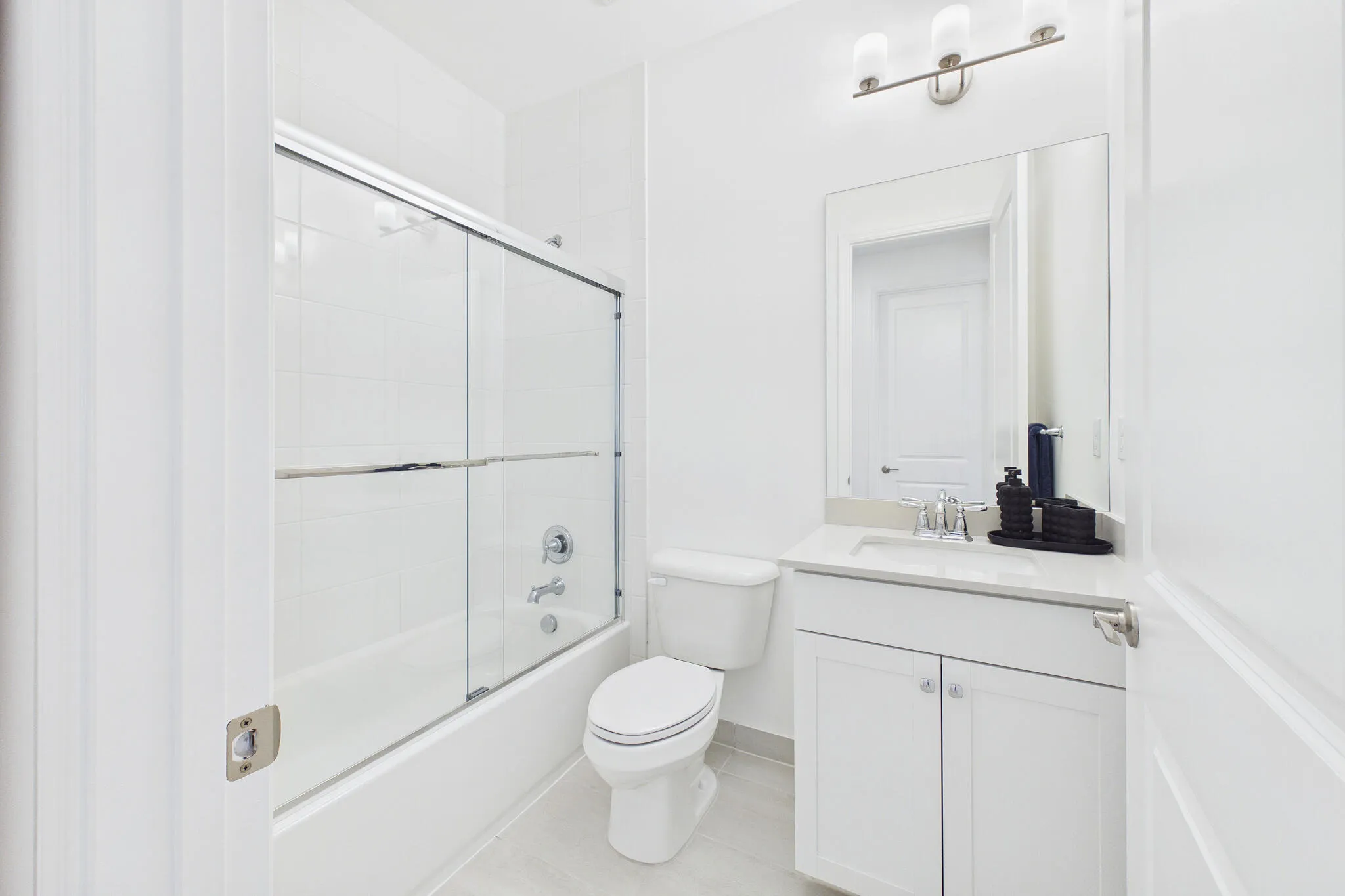 White vanity with a light-toned countertop, a rectangular mirror, and a three-light fixture