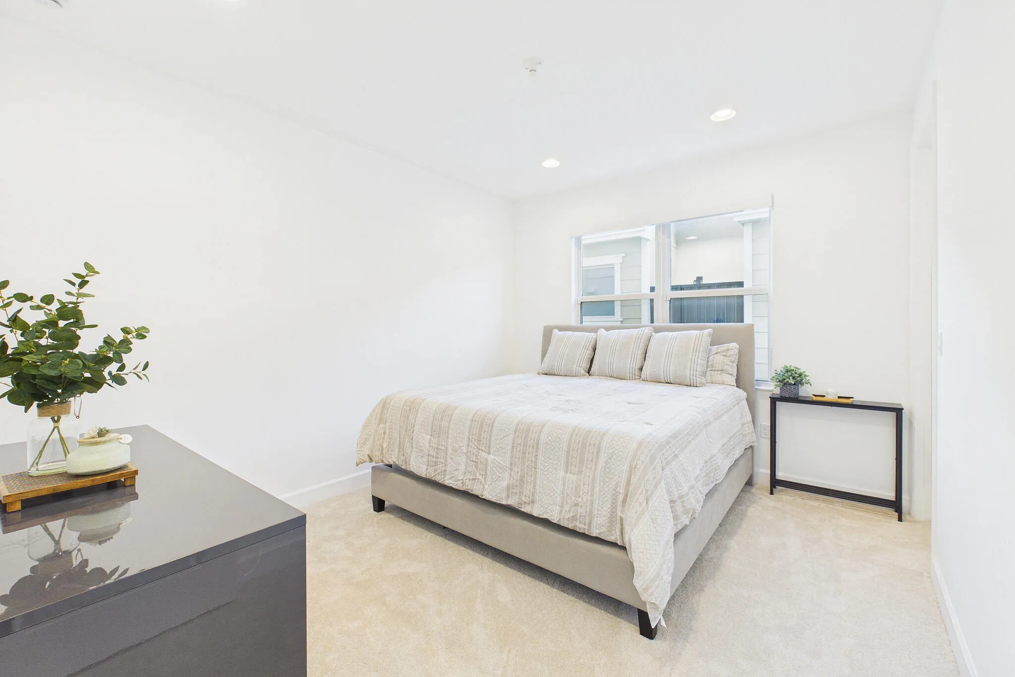 Recessed ceiling lighting, a large window, light-toned carpeting, and white wall finishes