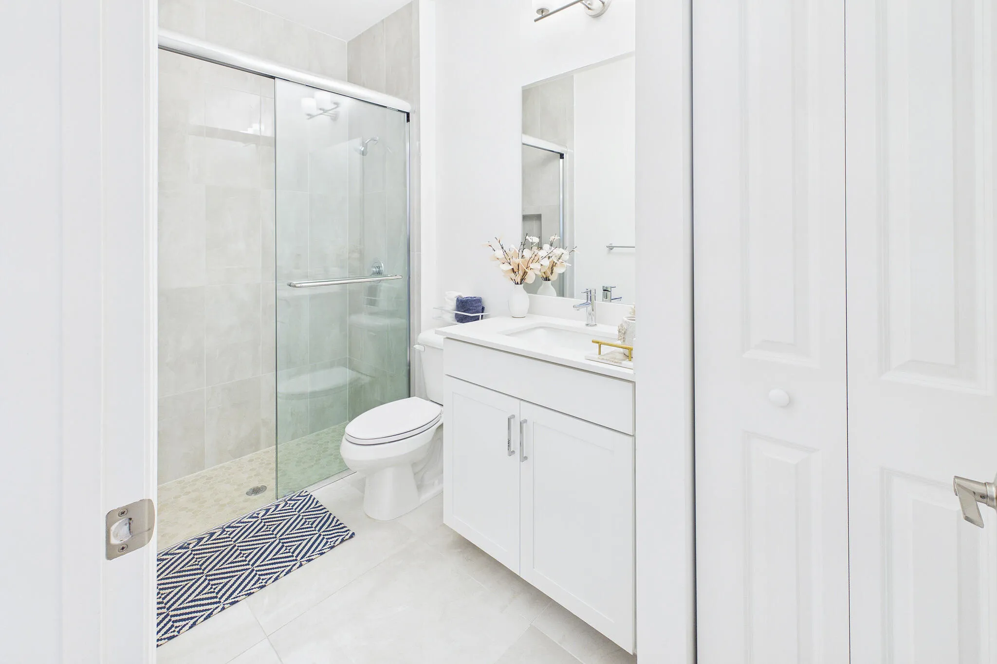 White vanity with an integrated sink, polished chrome faucet, and mirrored medicine cabinet