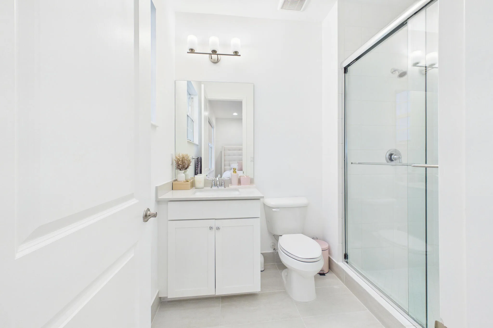 Bathroom featuring a glass-enclosed shower, white vanity with countertop, wall-mounted mirror, and overhead light fixture