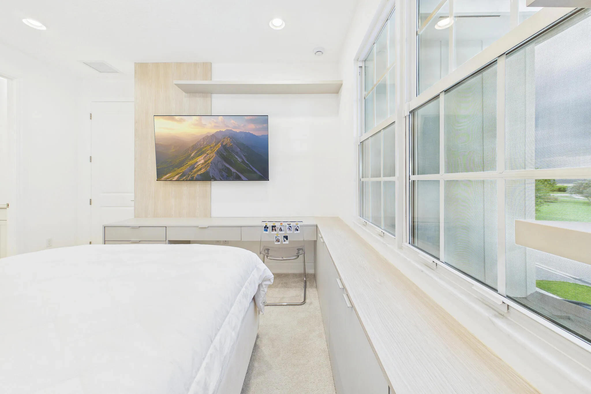 Built-in desk with integrated storage drawers, wood-finish accent wall, recessed lighting, double-hung windows, and a window-length storage bench