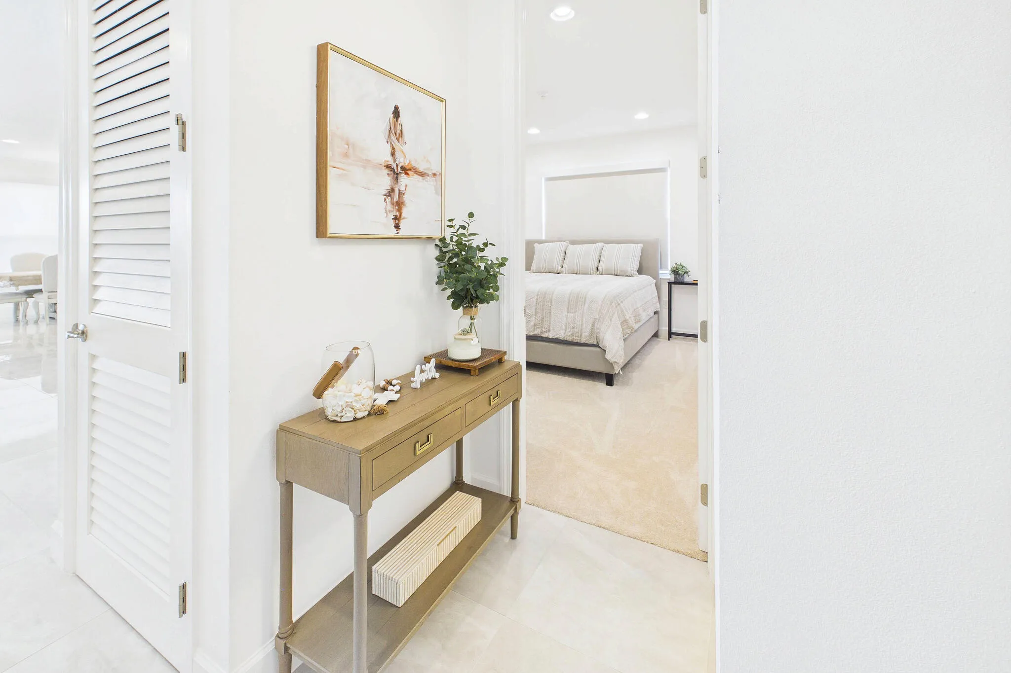 Louvered white interior door, light-toned wall finish, recessed lighting, and light-toned flooring throughout