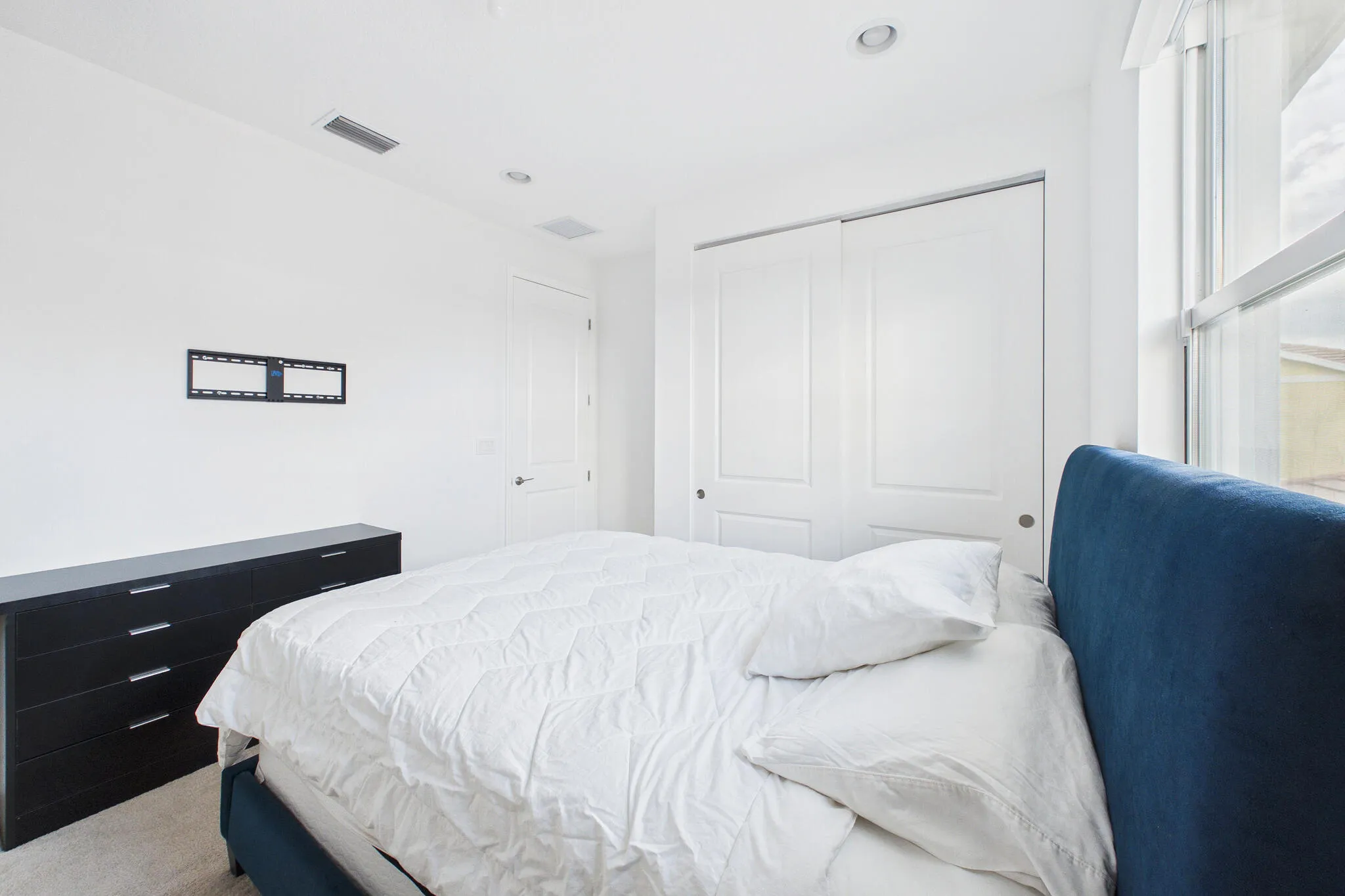 Recessed ceiling lighting, white interior door, closet with sliding doors, and window with white trim