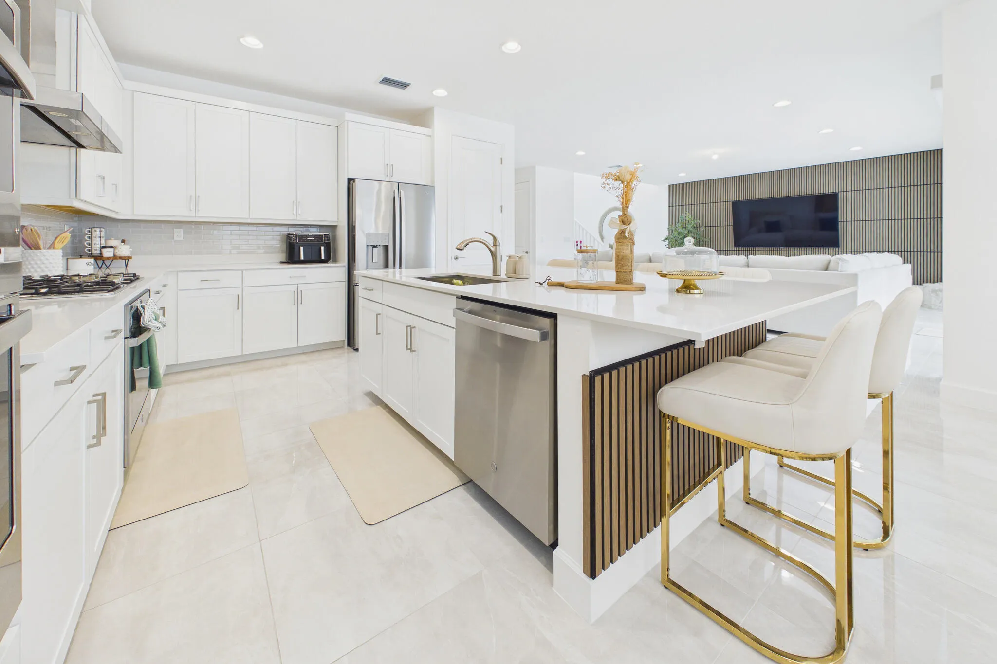 Kitchen featuring white cabinetry, stainless steel appliances, a tile backsplash, light-toned flooring, and an island with bar seating and decorative wood slat detailing
