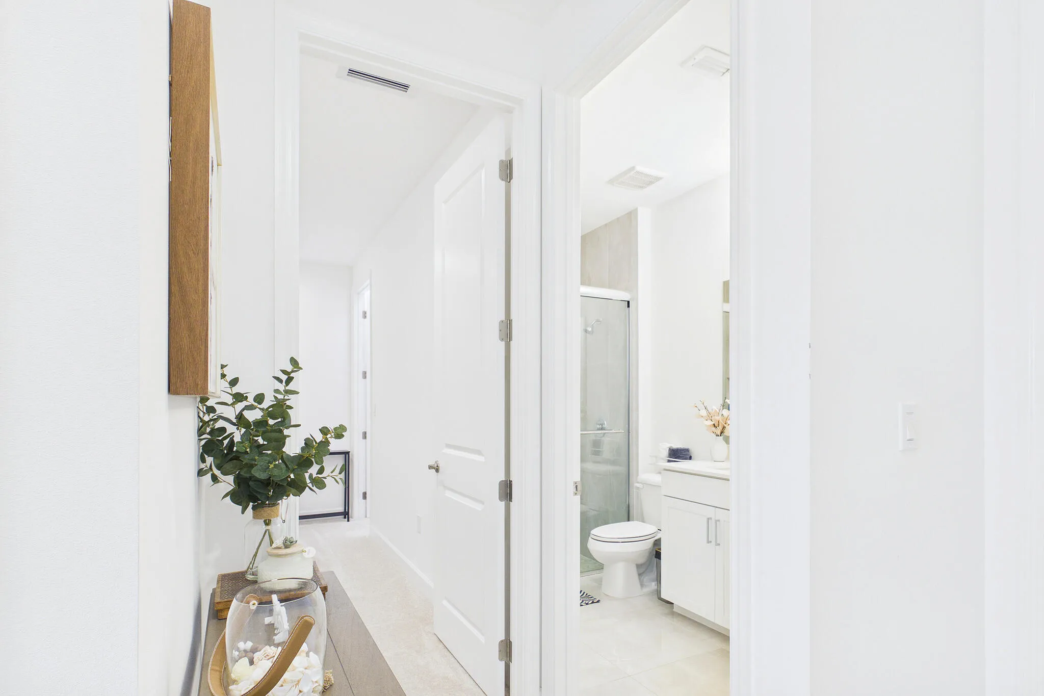 White-painted interior doors, light-toned flooring, and a modern bathroom vanity with a white countertop