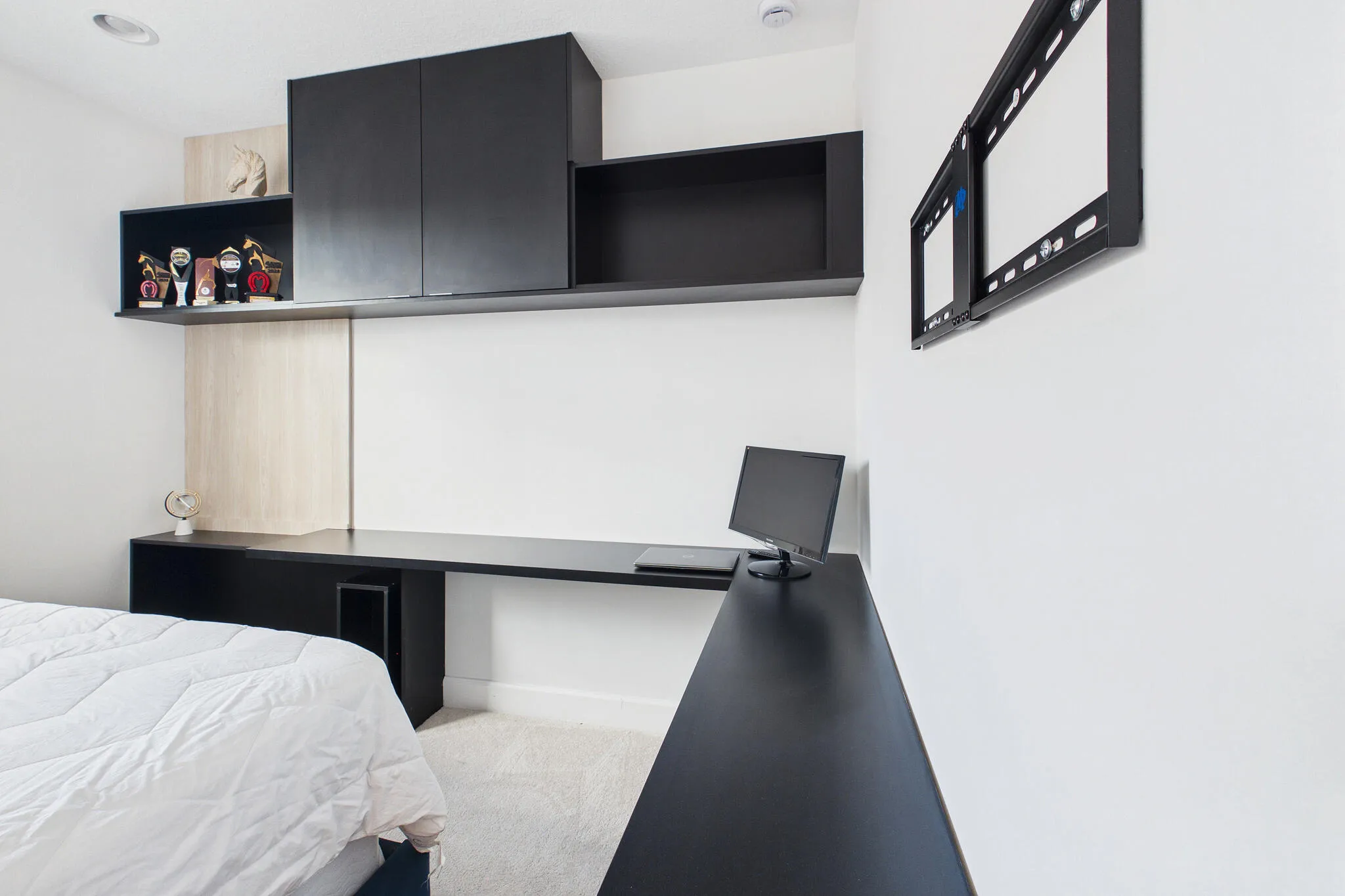 Built-in desk with dark finish, integrated shelving, dark cabinetry, light-toned wood-finish wall panel, and recessed lighting