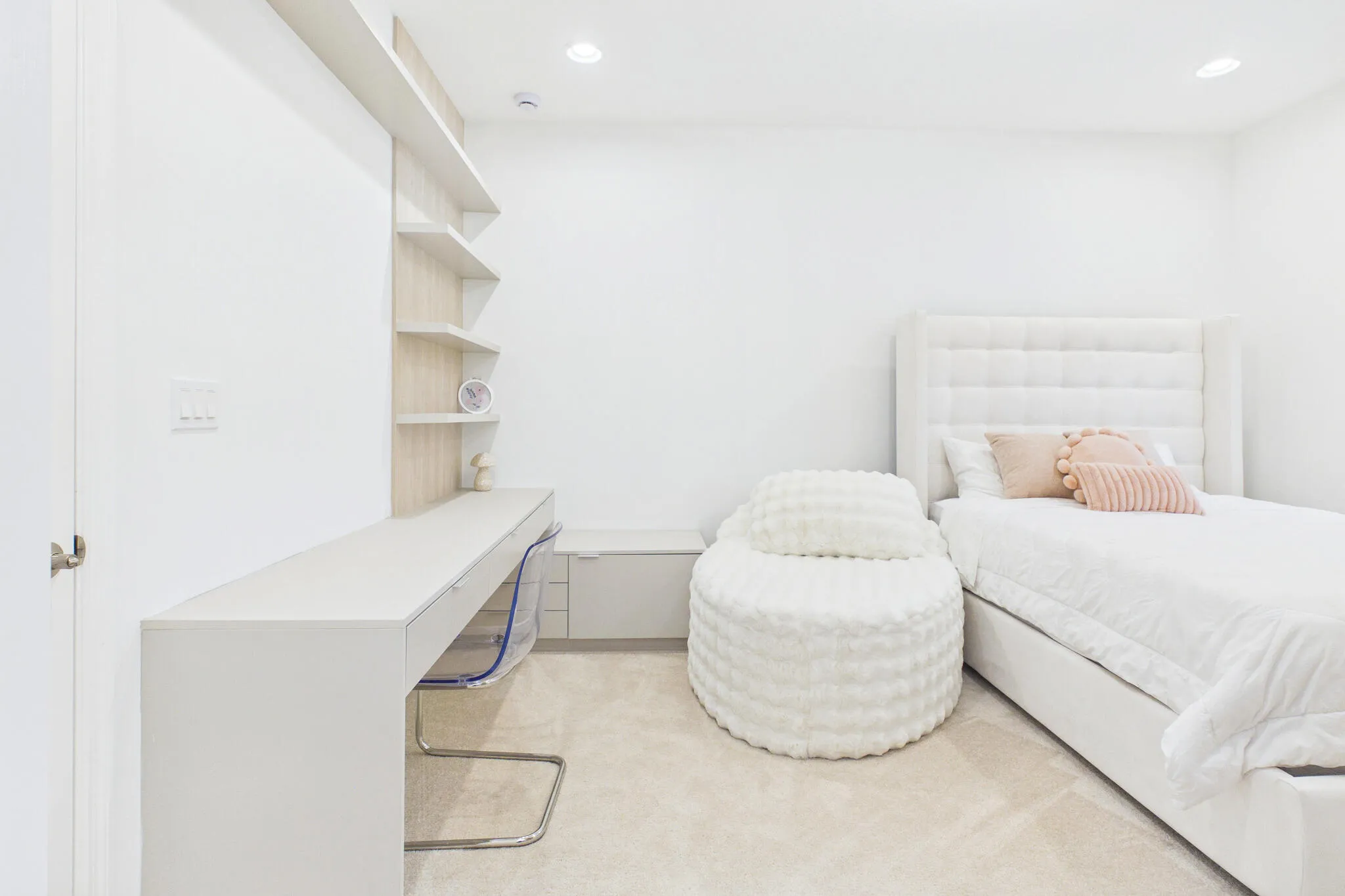 Built-in desk with integrated shelving, recessed lighting, wall-to-wall carpeting, and a paneled headboard