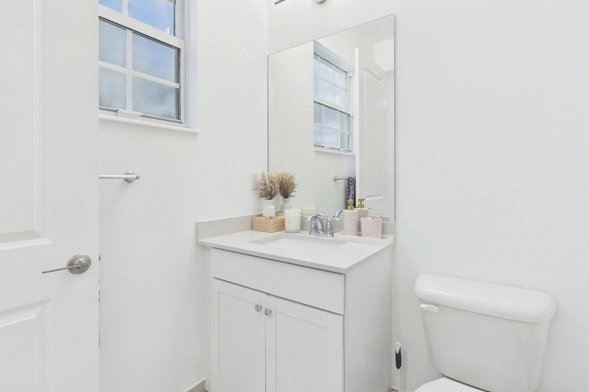 White shaker-style vanity with a light countertop, integrated sink, and chrome faucet