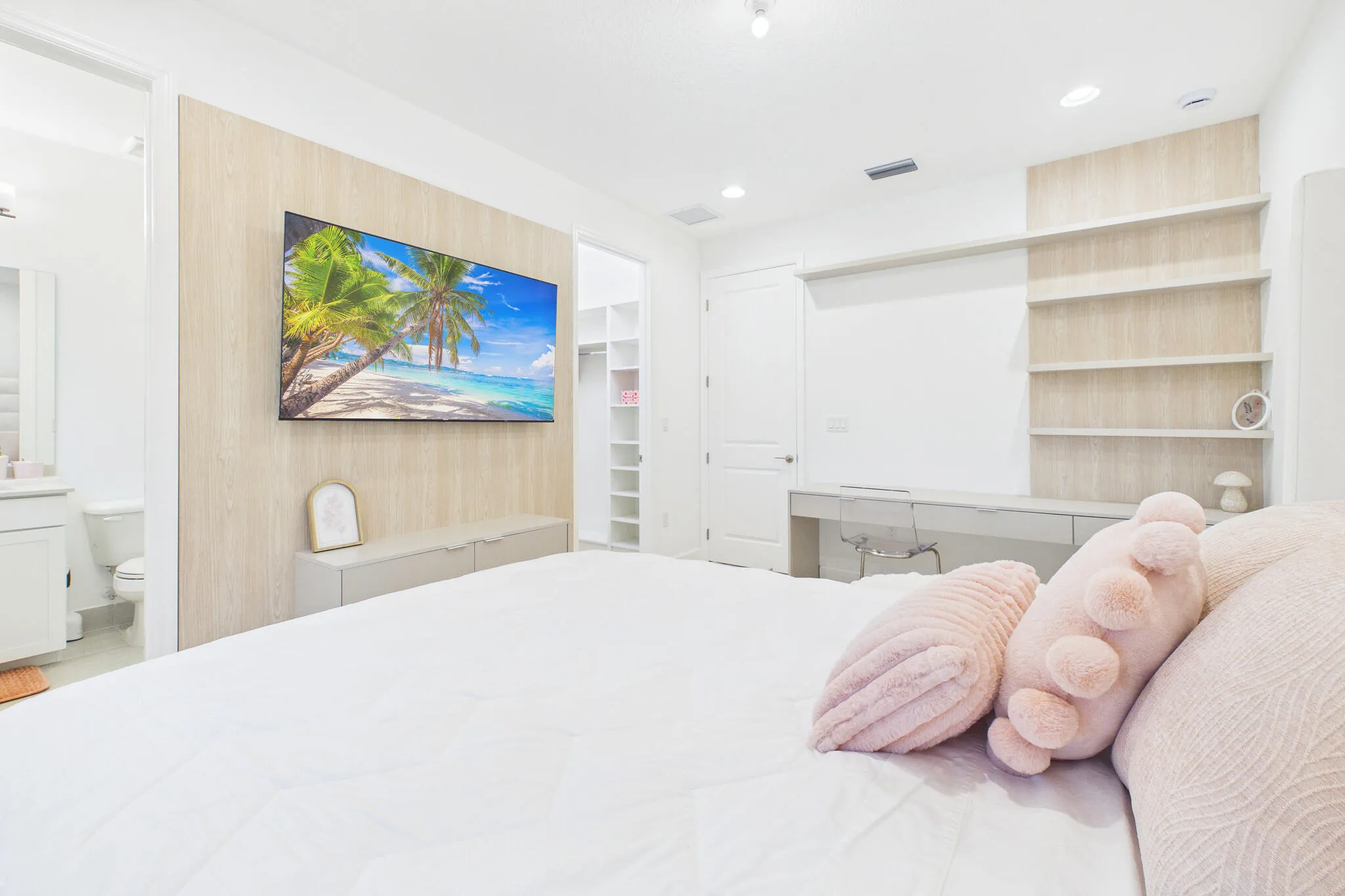 Wood-finish accent wall with integrated media console, built-in shelving, recessed lighting, and a dedicated desk area