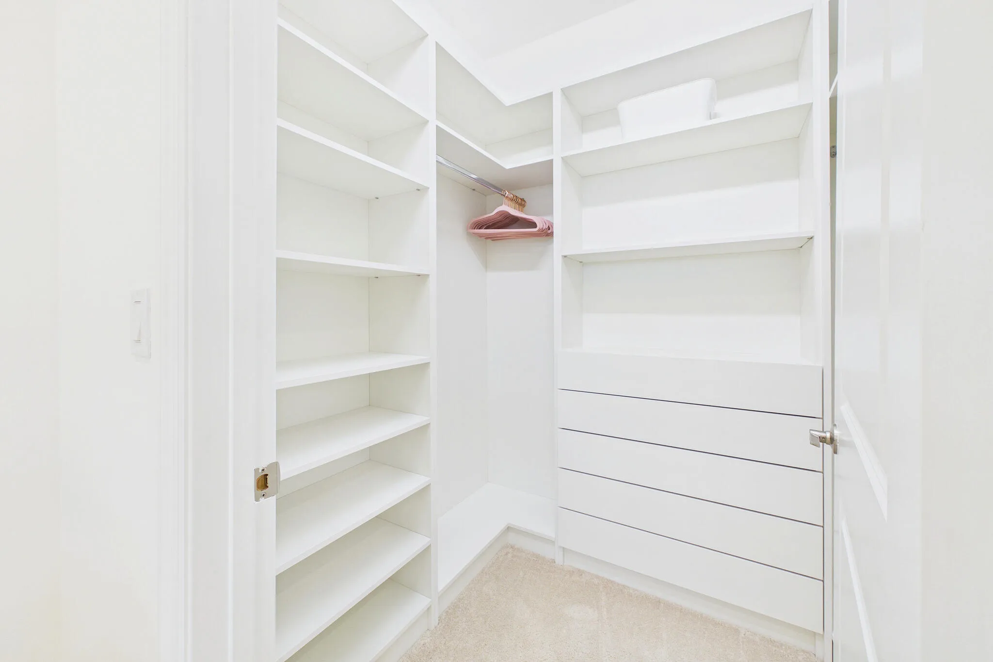 Built-in closet system featuring multiple shelving units, integrated drawers, and a hanging rod