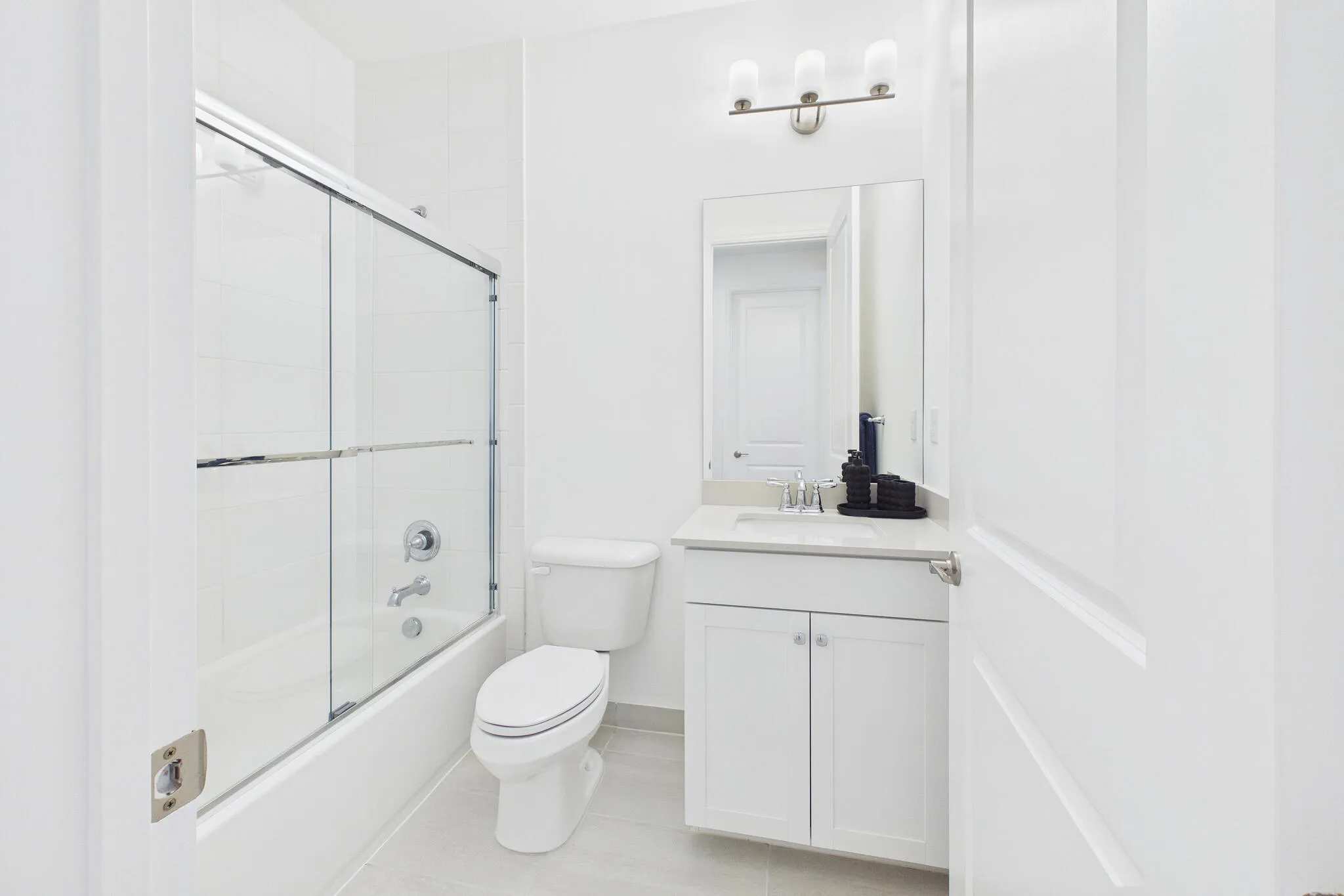 White vanity with undermount sink, wall-mounted mirror, and three-light vanity fixture