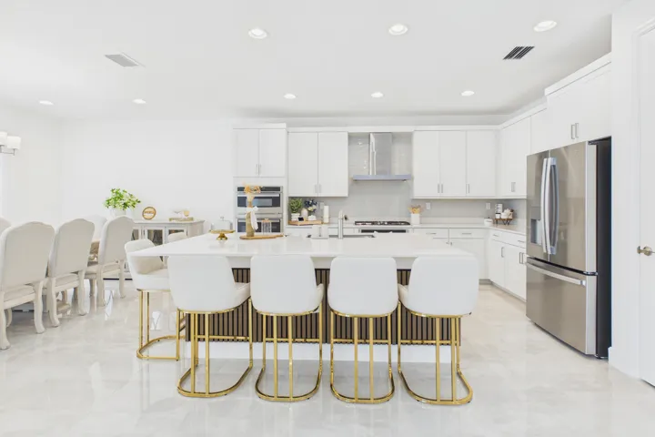 Gourmet kitchen with a large central island, stainless steel appliances, white cabinetry, and recessed lighting