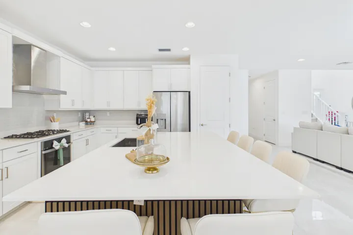 Kitchen featuring an expansive island with a solid surface countertop, white shaker-style cabinetry, stainless steel appliances, a tile backsplash, and recessed lighting