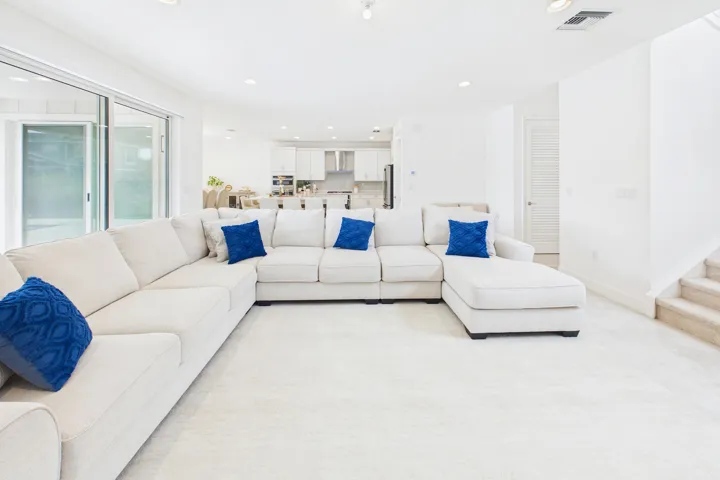 Spacious open-concept living area featuring light-toned carpeting and recessed lighting