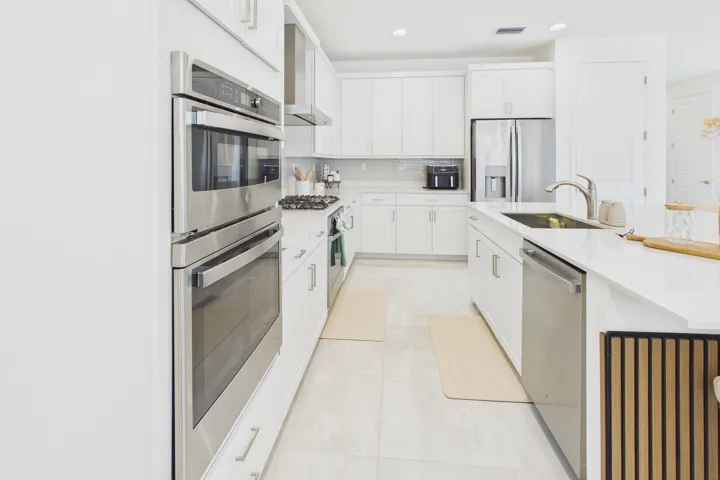 Modern kitchen featuring white cabinetry, stainless steel appliances, a center island with sink, and tile flooring