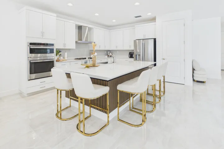 Gourmet kitchen with white cabinetry, stainless steel appliances, a large center island, and light-toned tile flooring