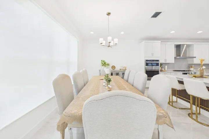 Open-concept living space with sleek tile flooring, a modern chandelier, and recessed lighting