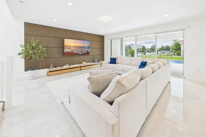 Open-concept living area with large format tile flooring, a wood-slat accent wall, recessed lighting, and expansive sliding glass doors