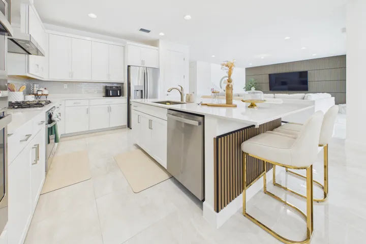 Kitchen featuring white cabinetry, stainless steel appliances, a tile backsplash, light-toned flooring, and an island with bar seating and decorative wood slat detailing
