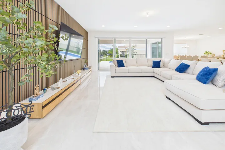 Recessed lighting throughout, tile flooring, wood-panel accent wall, built-in entertainment console, and sliding glass doors