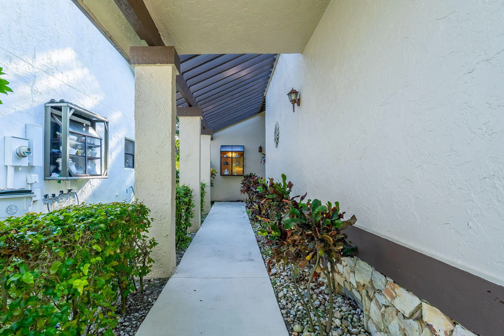Covered entryway with textured walls, columns, and an exterior wall lantern